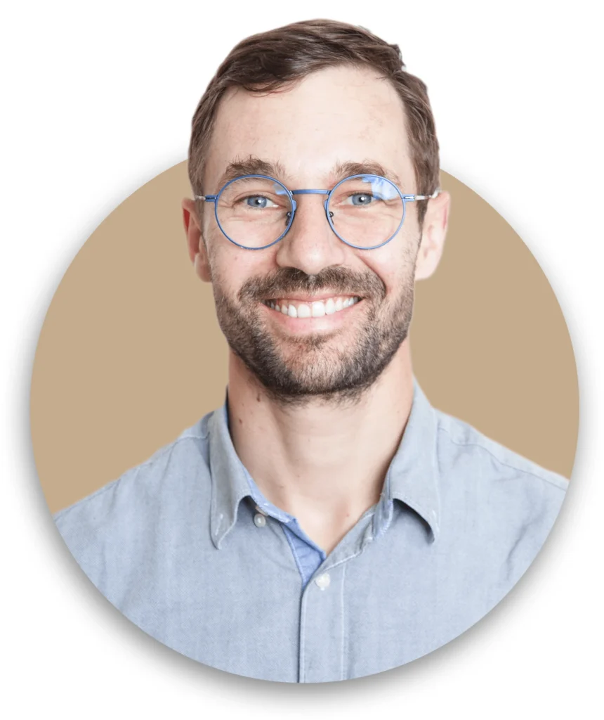 Homme souriant avec lunettes rondes.