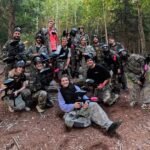 L’équipe Care Concierge en tenue de paintball après la partie, en forêt