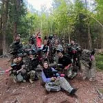 L’équipe Care Concierge en tenue de paintball après la partie, en forêt